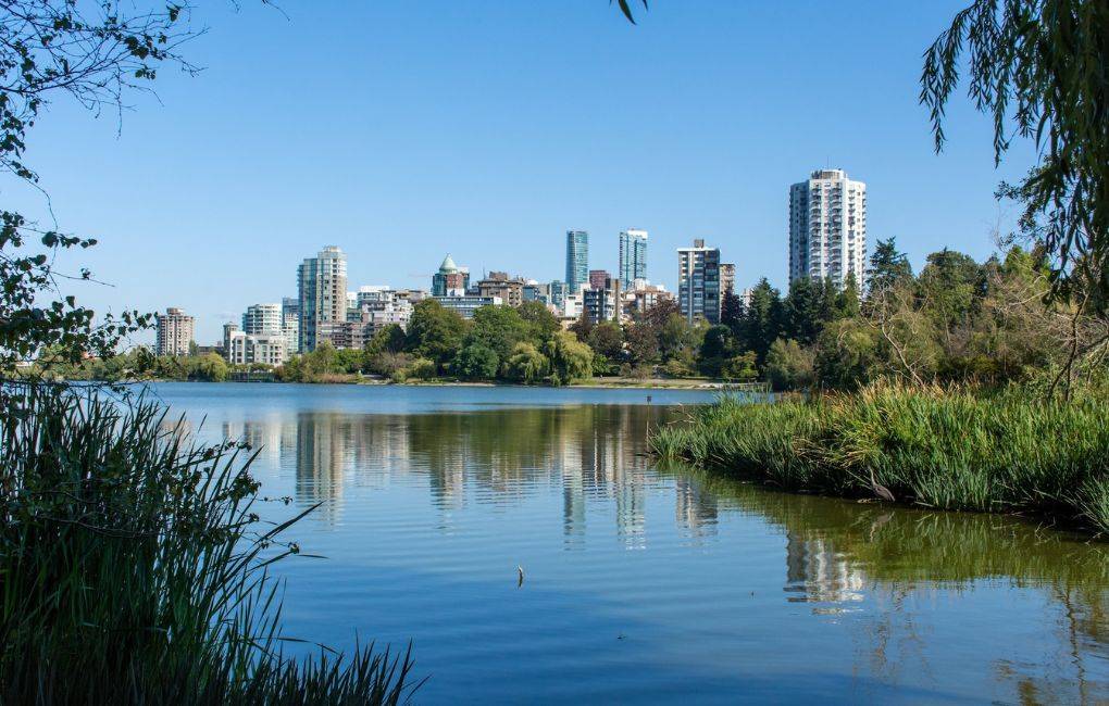 Lost Lagoon in Stanley Park in Vancouver, British Columbia, Canada looking towards downtown urban apartments near the beautiful summer nature.
